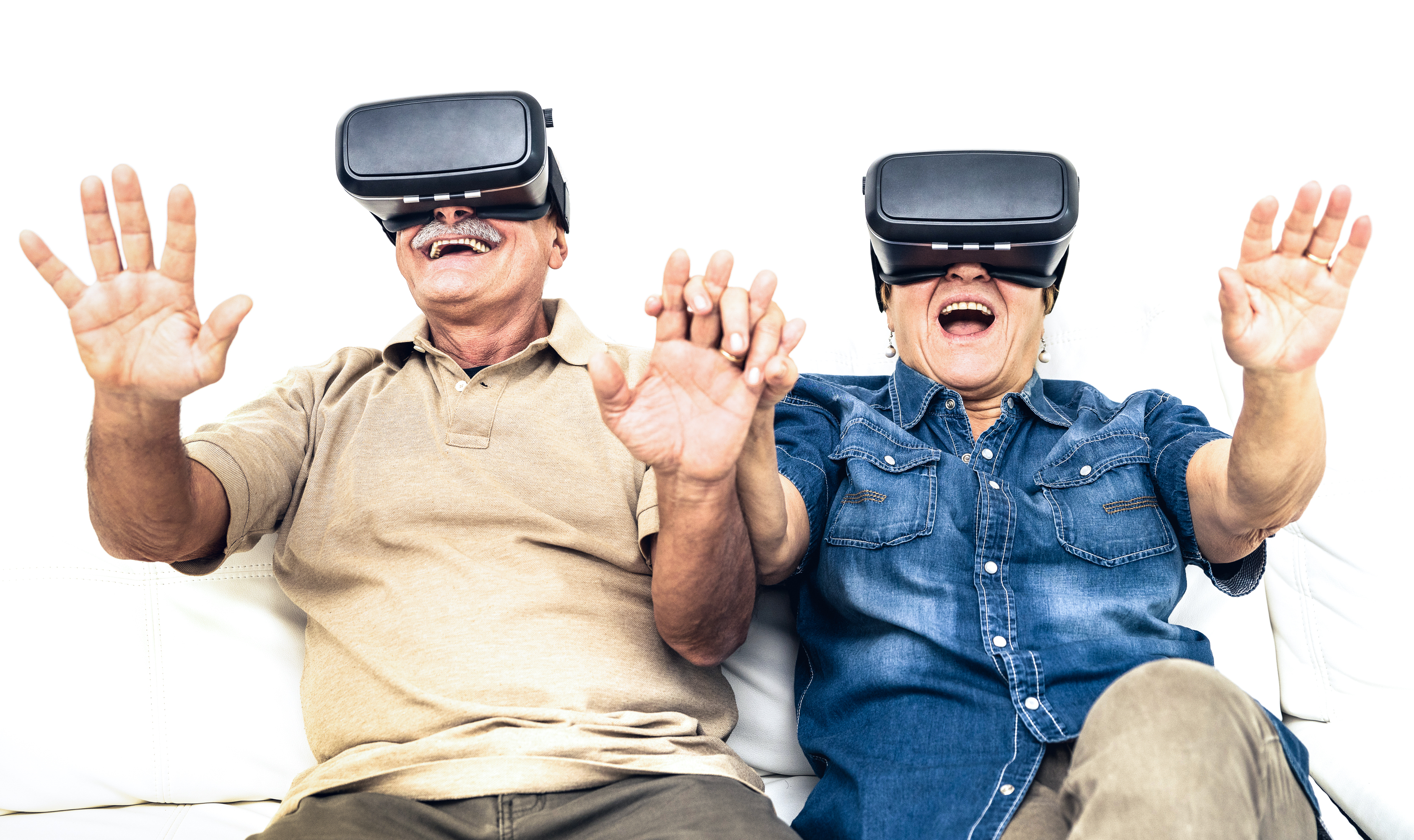Senior mature couple having fun together with virtual reality headset sitting on sofa - Happy retired people using modern vr goggle glasses - New trends and technology concept and funny active elderly